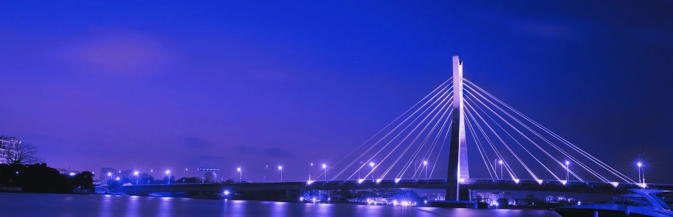 Night view of a cable-stayed bridge illuminated in violet blue